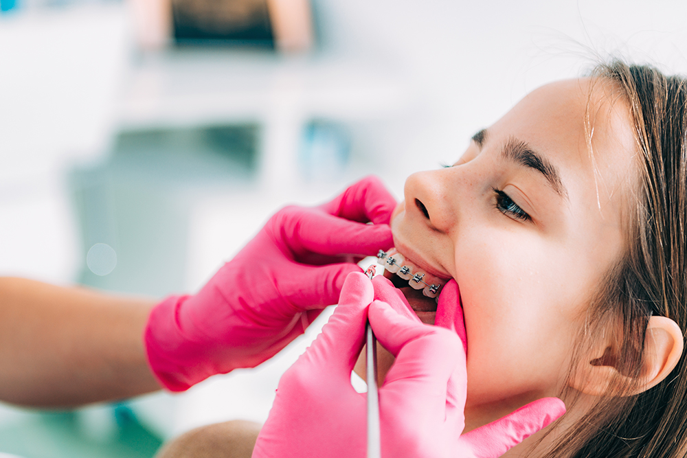 Orthodontist checking girl’s dental braces Ortodontia