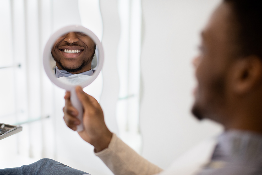 New Smile. Black Man Looking At Mirror While Sitting In Dentist Chair Oclusão e ATM