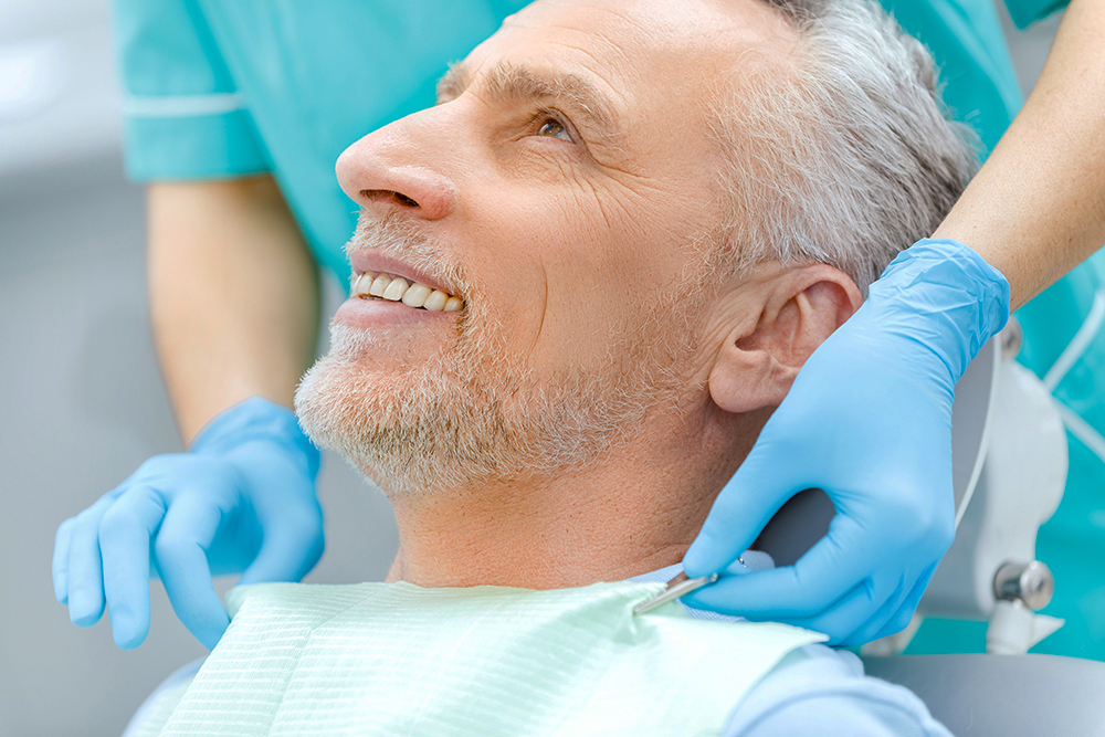 Cropped shot of smiling mature patient and dentist in medical gl Medicina e Patologia oral