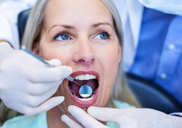 Dentist examining a woman with tools in dental clinic Medicina e Patologia oral