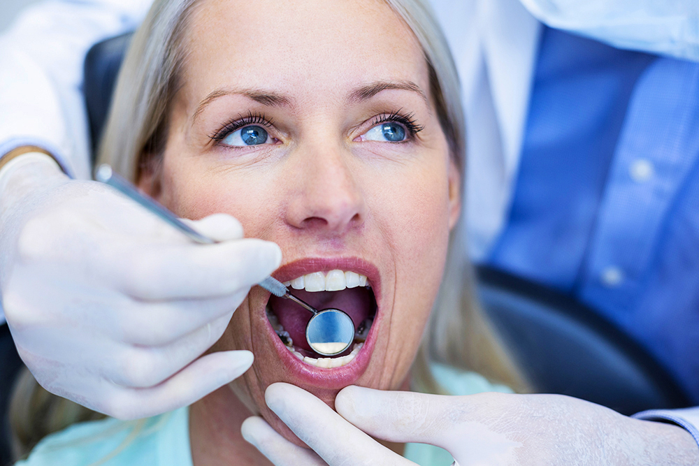Dentist examining a woman with tools in dental clinic Medicina e Patologia oral