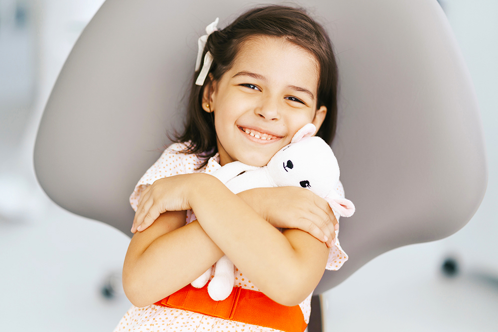 Smiling cute girl in dentist chair Odontopediatria